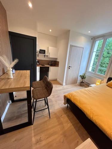 a bedroom with a bed and a desk and a kitchen at Le Nid douillet Nancéien in Nancy