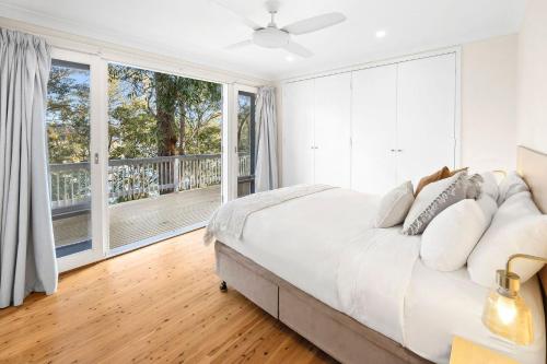a bedroom with a large bed and a large window at Treetop Retreat Northern Beaches with Stunning Pittwater Bay Views in Newport