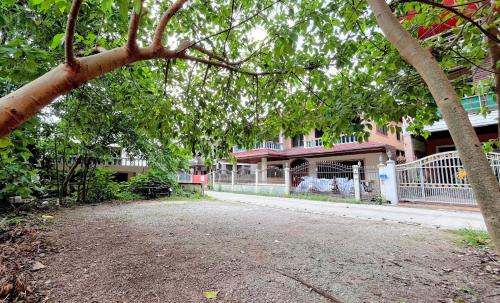 a tree in front of a building with a fence at Coco Mountain View Guest House Hotel in Kata Beach