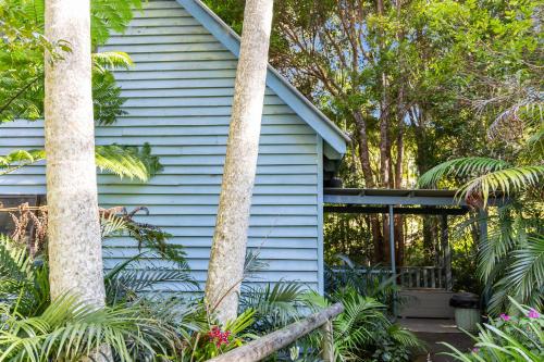 a blue house with palm trees in front of it at Montville Country Cabins in Montville