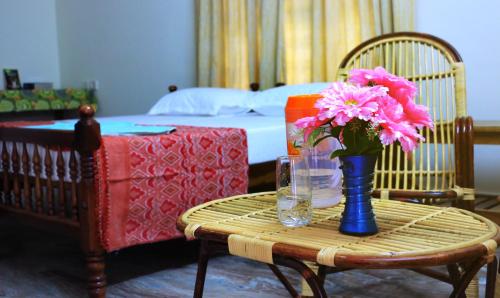 une table avec un vase de fleurs roses sur elle dans l'établissement Silent Villas, à Varkala