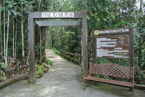 a sign that says trail to the farm with a bench at Homestay Murah Lahad Datu in Lahad Datu