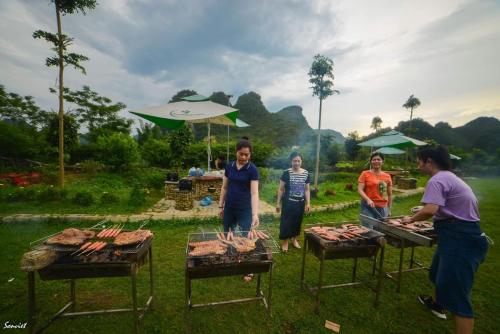 a group of people standing around a grill at Nasan Green Farm in Cao Bằng