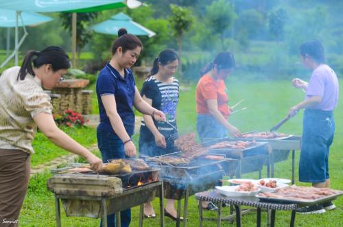 a group of people cooking food on a grill at Nasan Green Farm in Cao Bằng