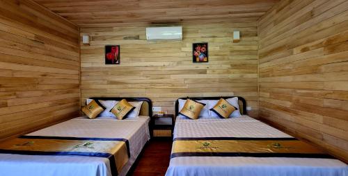 two beds in a room with wooden walls at Nasan Green Farm in Cao Bằng