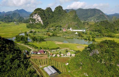 an aerial view of a resort with a river and mountains at Nasan Green Farm in Cao Bằng