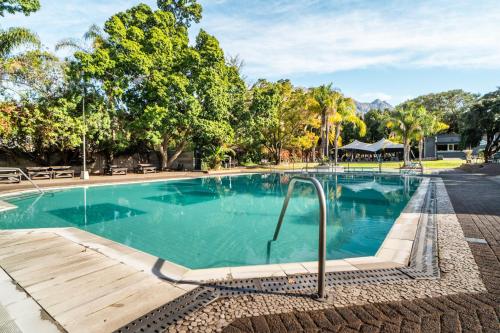 a large swimming pool with a wooden deck and trees at ATKV Goudini Spa in Rawsonville