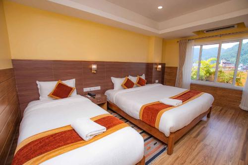 a hotel room with two beds and a window at Hotel Hidden Kingdom in Pokhara