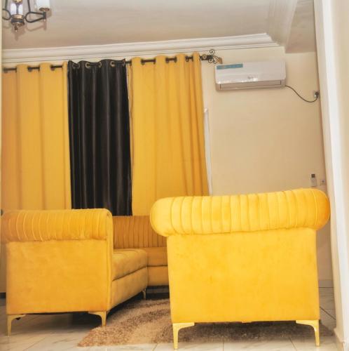 two yellow chairs and a couch in a room at Supreme hosts in Yaoundé