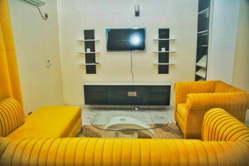 a living room with two yellow couches and a tv at Supreme hosts in Yaoundé