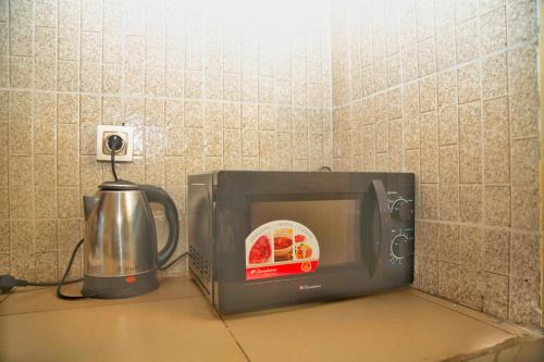 a microwave sitting on a counter next to a kettle at Supreme hosts in Yaoundé