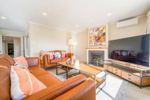 a living room with leather furniture and a fireplace at Three-Bedroom Home in Somerville in Auckland