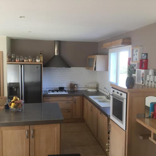 une cuisine avec des armoires en bois et un réfrigérateur noir dans l'établissement Maison familiale en OCCITANIE, à Névian