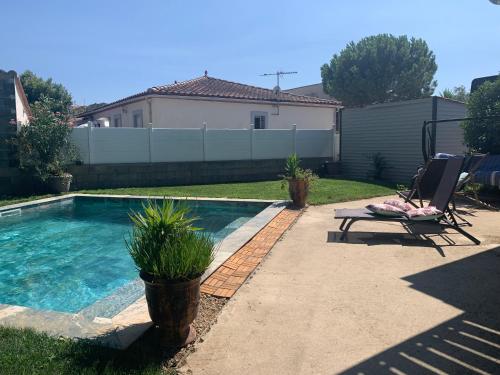 une cour avec une piscine et une chaise longue dans l'établissement Maison familiale en OCCITANIE, à Névian