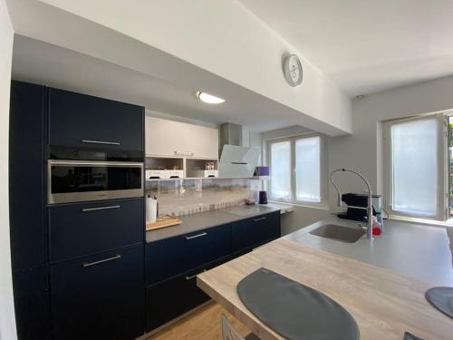 une cuisine avec des armoires noires et un comptoir dans l'établissement Charme et Confort pour 6 personnes à SOULAC, à Soulac-sur-Mer