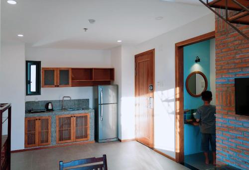 a boy standing in a kitchen with a mirror at Laholm Hotel - Apartment in Nha Trang