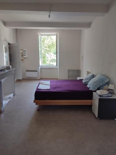 - une chambre avec un lit doté de draps violets et une fenêtre dans l'établissement Grand appartement à Anduze - Cevennes Flat, à Anduze