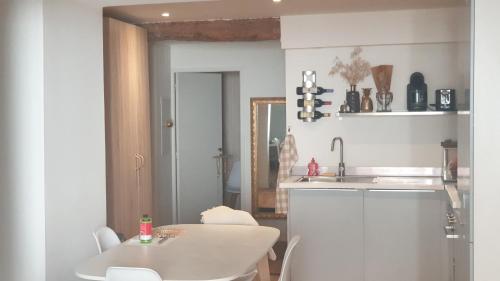- une cuisine blanche avec une table et un évier dans l'établissement Gîtes Les 3 Tours, à Carcassonne
