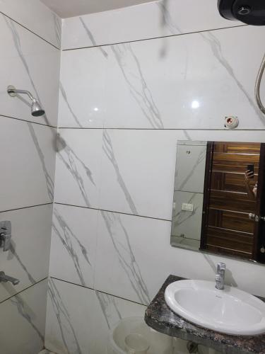 a white bathroom with a sink and a mirror at Pinnacle Hotel in Phagwāra