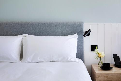 a white bed with white pillows and a lamp at Manly Pacific Sydney MGallery Collection in Sydney