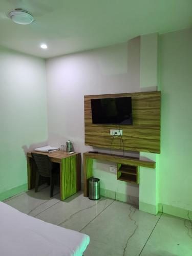 a room with a desk and a television on a wall at Pinnacle Hotel in Phagwāra
