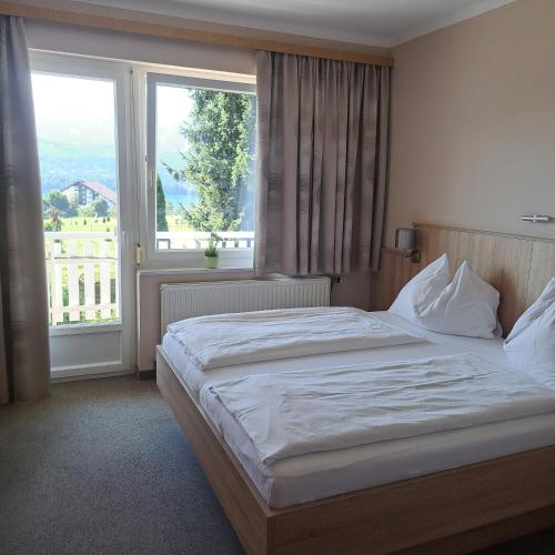 a bedroom with a bed and a large window at Haus Panorama in Drobollach am Faakersee