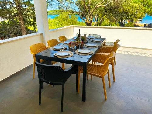 a black table with chairs and wine bottles on a patio at Holiday home Prora Mare in Ždrelac