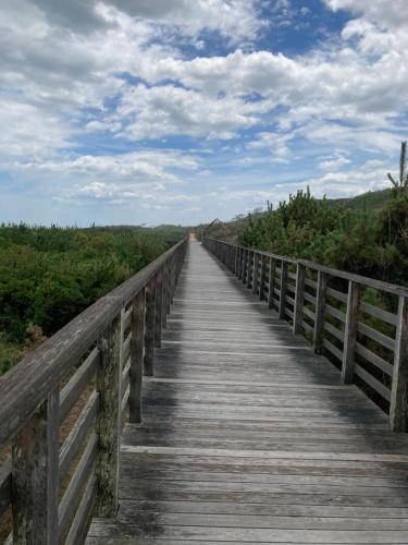 a wooden bridge over a field with a blue sky at サンムーン in Kumiage