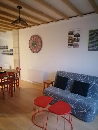 un salon avec un canapé et une horloge au mur dans l'établissement La Grange de la Gandonnerie, à Baugé