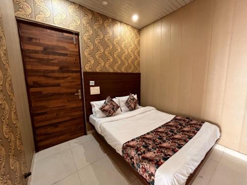 a bedroom with a bed and a wooden door at Hotel Pearl Grand-Family Hotel-Feel Like home in Zirakpur