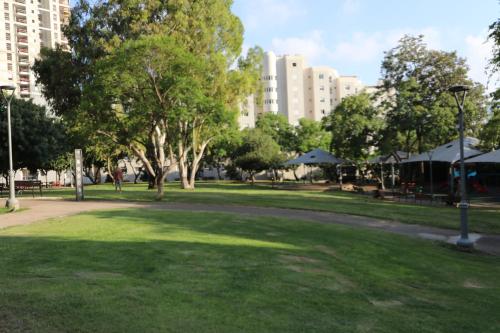 a park with green grass and trees and buildings at Assuta family in Tel Aviv