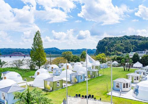 a group of domes and tents on a field with a river at Takatakiko Glamping Resort in Tsurumai