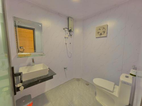 une salle de bain blanche avec un lavabo et des toilettes dans l'établissement Săn Mây Coffee and Homestay Măng Đen, à Kon Von Kla