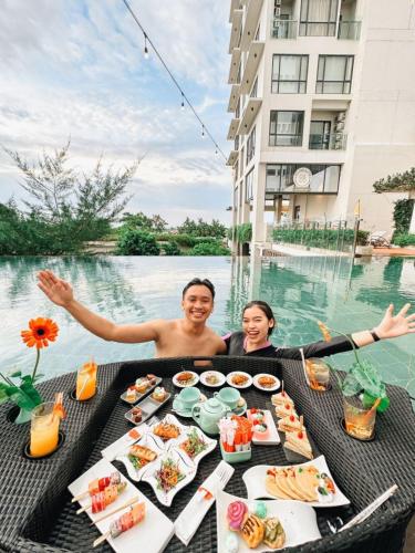 two people sitting at a table with food in the water at HARRIS Hotel Batam Center in Batam Center