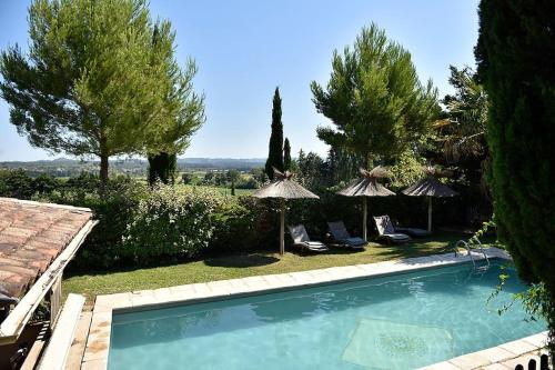 - une piscine dans une cour avec des parasols dans l'établissement Le Mazet des Oliviers, à Arles
