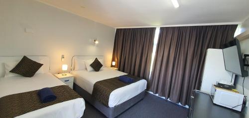 a hotel room with two beds and a flat screen tv at Silver Oaks Motel in Gilgandra