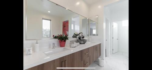 a white bathroom with two sinks and a mirror at Costa Mesa Cozy Retreat, Modern and Smart Home in Costa Mesa
