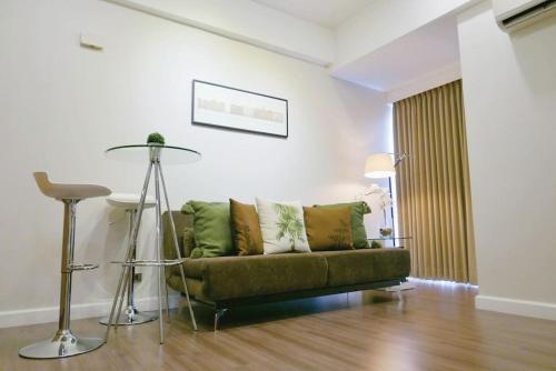 a living room with a green couch and a table at Modern 1BD Executive Suite, Netflix Wifi Pool Gym in Manila