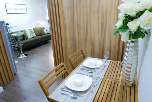 a table with plates and glasses and a vase with flowers at Modern 1BD Executive Suite, Netflix Wifi Pool Gym in Manila
