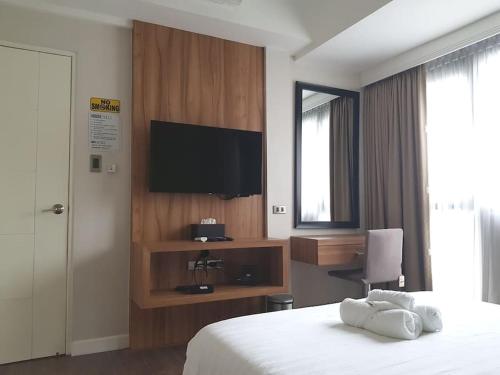 a hotel room with a bed and a flat screen tv at Modern 1BD Executive Suite, Netflix Wifi Pool Gym in Manila