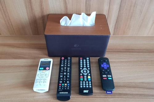 four remote controls and a box on a table at Modern 1BD Executive Suite, Netflix Wifi Pool Gym in Manila