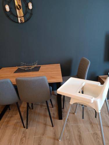 a dining room table with chairs and a clock on the wall at XL apartments, Residence Hill, Kopaonik in Kopaonik