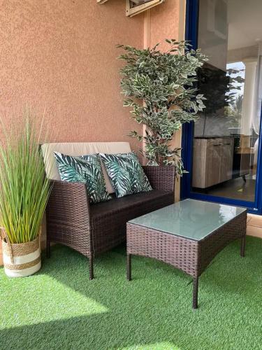 a wicker couch with a table and potted plants at Chez Gerard in Saint-Pierre
