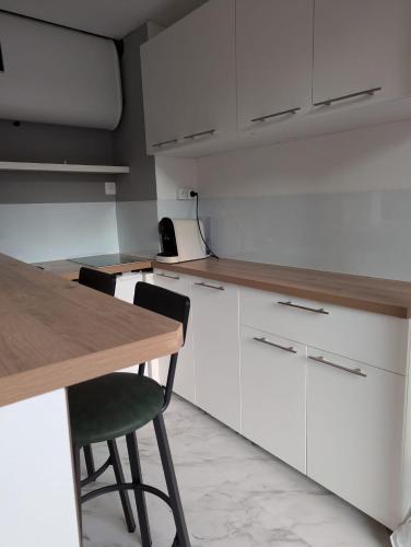 une cuisine avec des armoires blanches et une table en bois dans l'établissement T1 bis de 30 m2 avec terrasse, à Toulouse