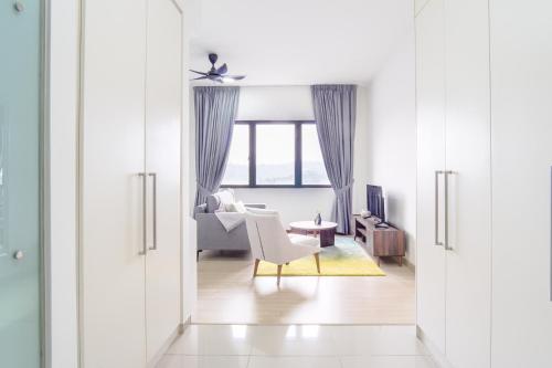 a white living room with a chair and a table at Encorp Strand Residences by Airhost in Kota Damansara