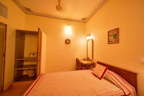 a bedroom with a bed and a table and a mirror at Hotel Arya Niwas in Jaipur