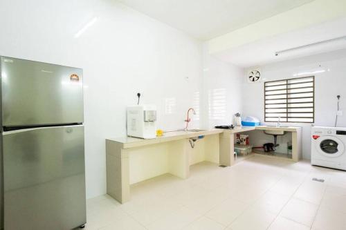 a white kitchen with a refrigerator and a microwave at Sweet 9ight Menglembu Falim Homestay in Ipoh