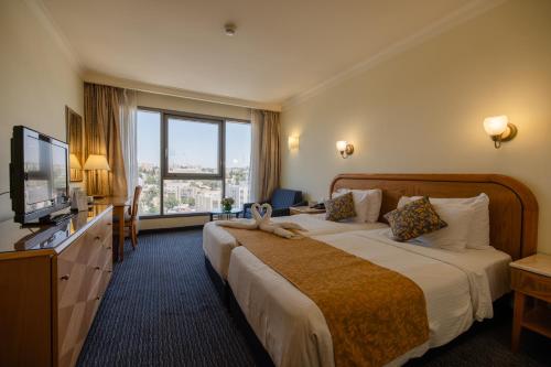 a hotel room with a large bed and a television at Grand Court Hotel in Jerusalem