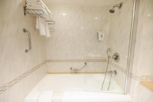 a white bathroom with a shower and a tub at Grand Court Hotel in Jerusalem