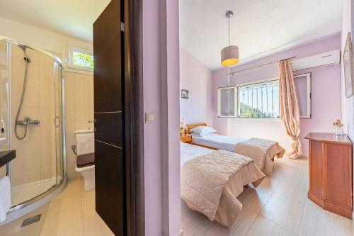 a bedroom with two beds and a bathroom with a shower at Villa Salvia in Katávolos
